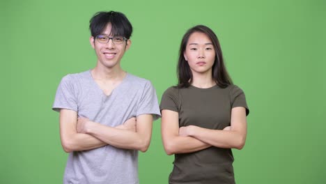 young happy asian couple together with arms crossed