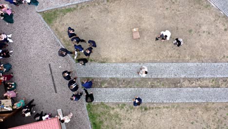 Groom-tossing-garter-to-group-of-men-at-outdoor-wedding,-overhead