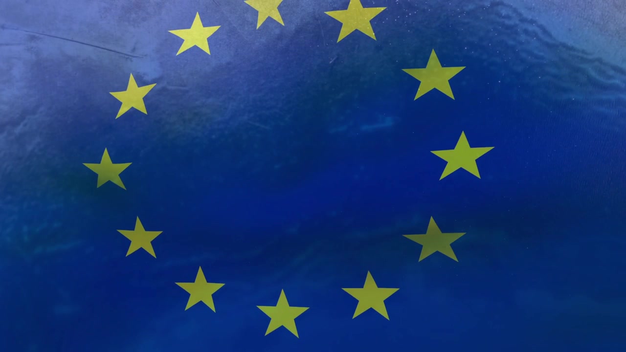 La telecamera effettua spostamenti laterali e un leggero zoom, il tessuto si increspa, l'emblema dell'UE si centra, rivelando le stelle.