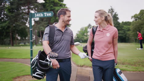 mature couple playing golf carrying golf bag and talking