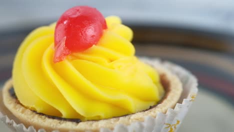 primer plano de una tarta amarilla con cereza roja