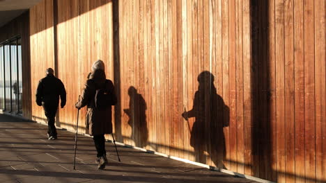 people in beanie and jacket walking in the hallway of a building sunlit on a cold sunset in oslo, norway