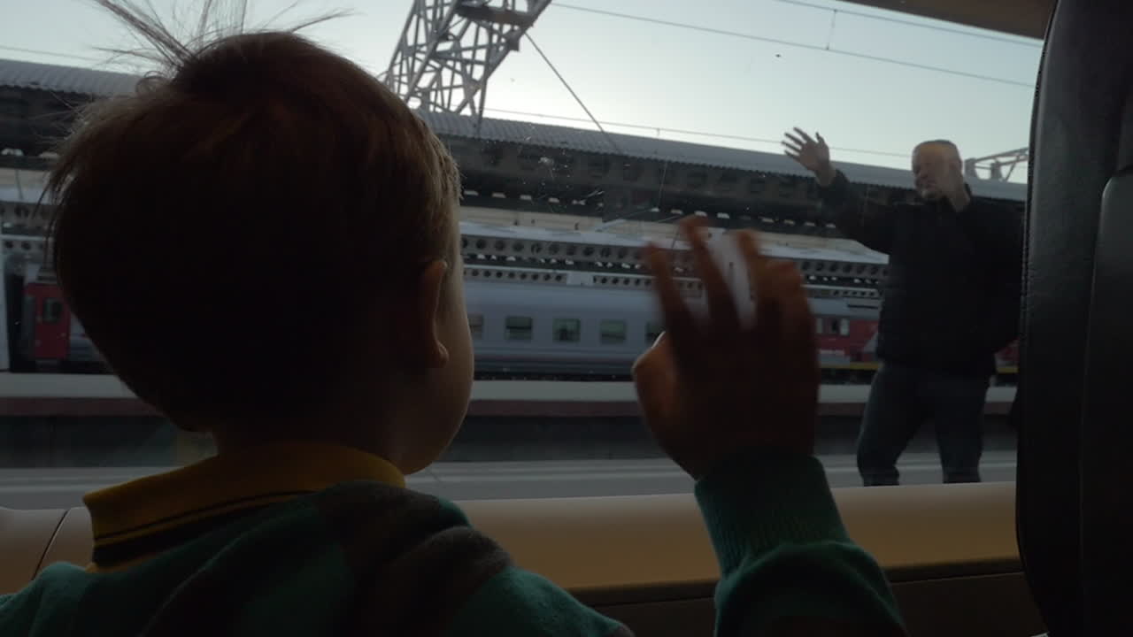 기차에서 아이가 할아버지와 할머니에게 손을 흔들며 떠나고 있다