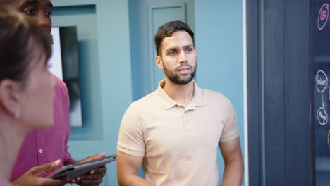 presenting ideas, man pointing at whiteboard while colleagues listen attentively