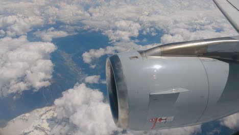 Image-from-the-airplane-window,-close-up-of-the-turbine,-passing-above-the-clouds-over-the-Swiss-Alps