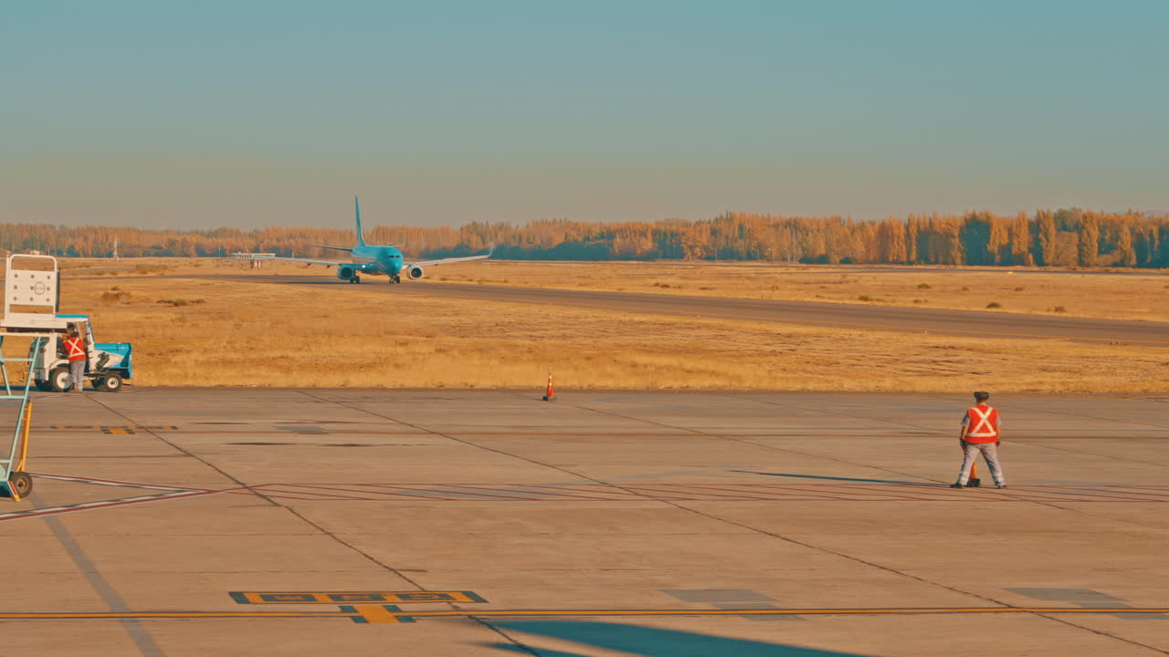 Aereo blu in rullaggio sulla pista dell'aeroporto con il personale di terra