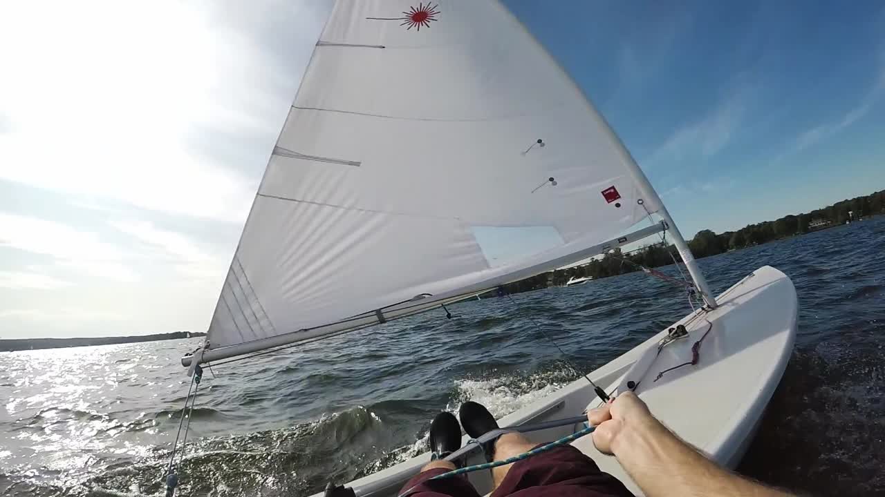 POV shot of sailing a laser sail boat on lake Wannsee in Berlin Germany, gusty wind, slow motion
