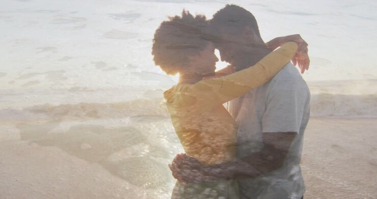 Woman wrapping arms around man starting embrace on beach, waves overlaying silhouettes for ad