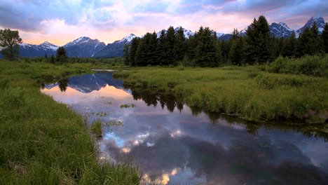 sky, mountain peak and forest reflecting on river at grand teton national park