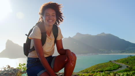 portrait of woman with backpack on vacation taking a break on hike by sea on coastal path