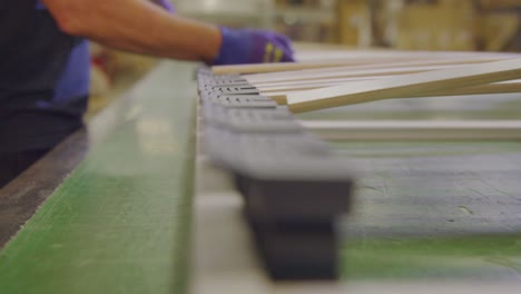 worker's hands sorting wooden slats in a boxspring bed factory, close-up