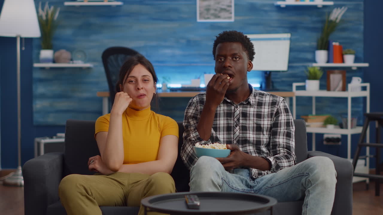 POV di una coppia interrazziale che guarda un film in TV con uno snack