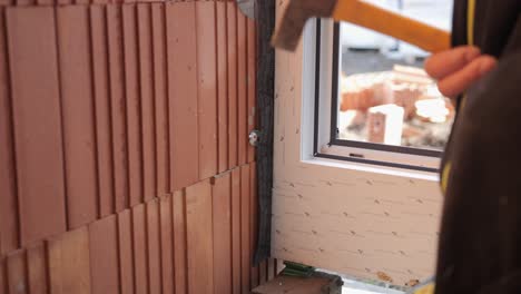 a hole is drilled in a brick wall and a nail is hammered in the slab brick wall, construction site worker craftsman working contractor skills