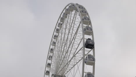 large ferris wheel slowly turning against gray overcast sky