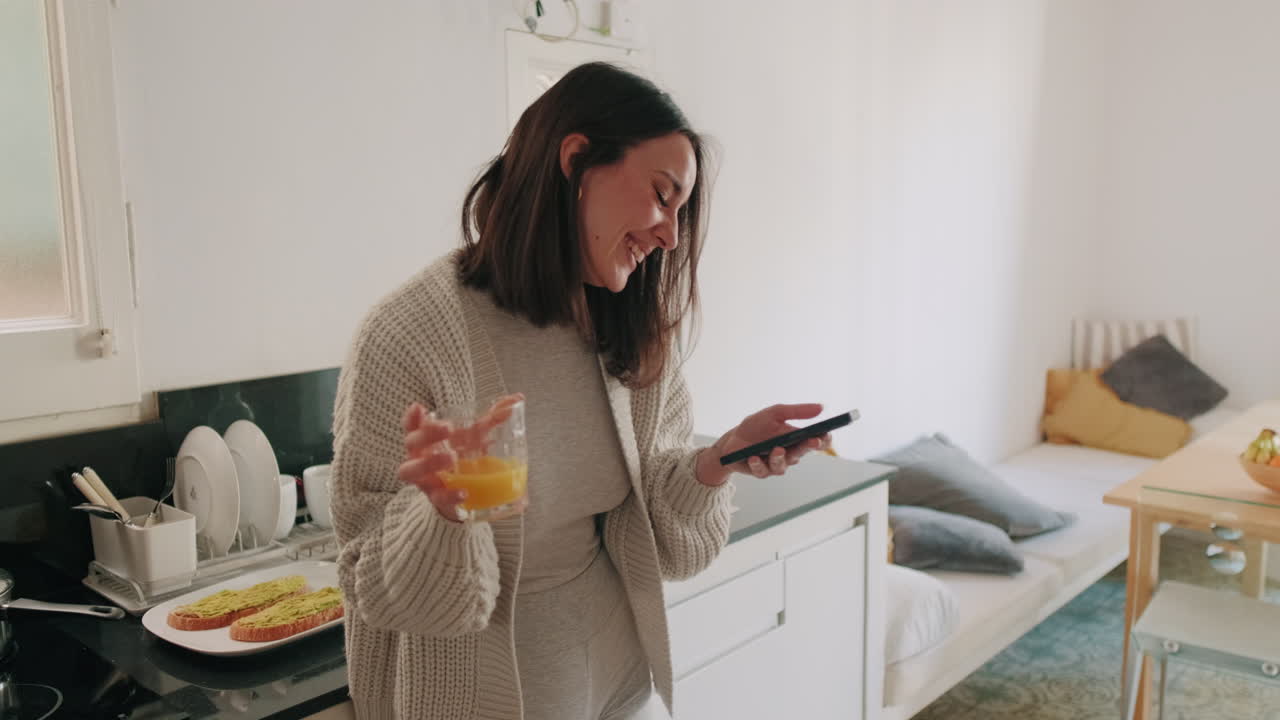 Donna che beve il succo d'arancia in cucina