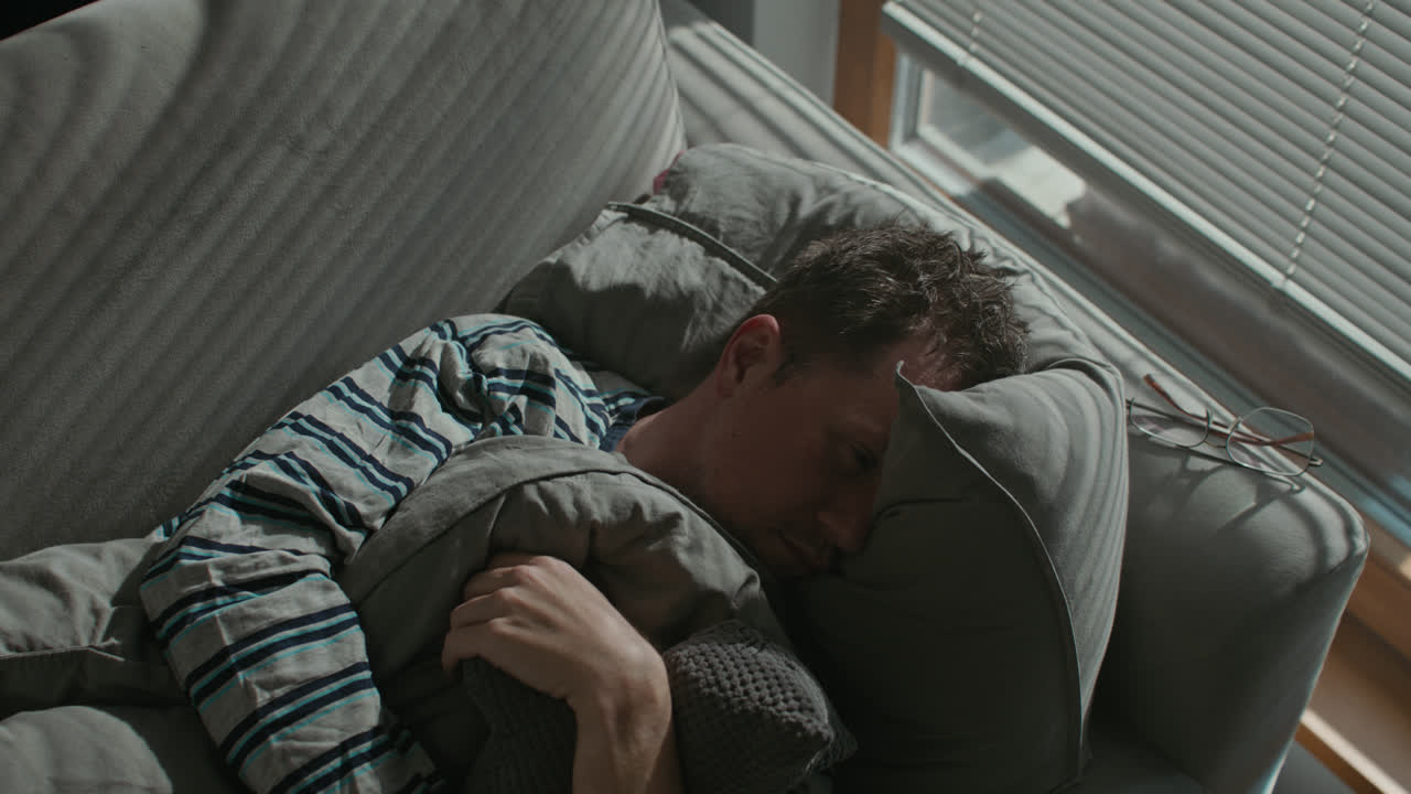 A sad man wakes up tired on his sofa