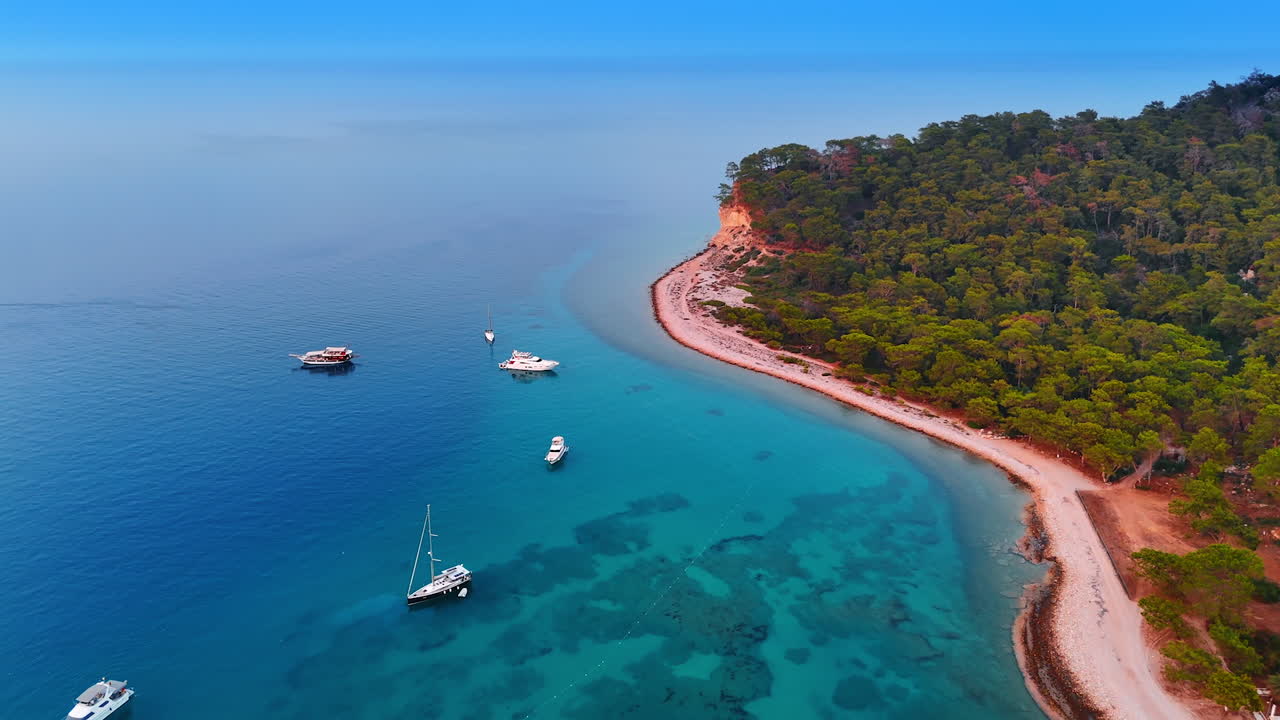 Drone flight over the sandy beach in Turkey. Yachts are on the blue waterscape of the Mediterranean