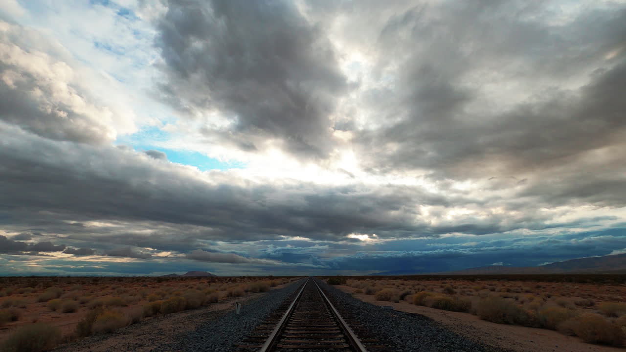 The view of beautiful clouds rolling over a train track across the Mojave desert in California - Time lapse