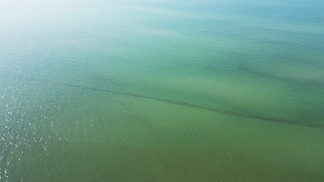 Toma-Aérea-De-Sobrevuelo-De-Aguas-Tranquilas-Y-Cristalinas-Del-Océano-Durante-El-Día.