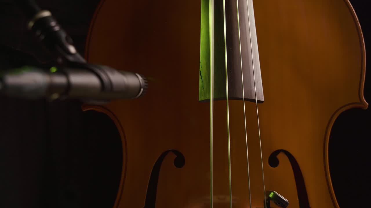 manos masculinas tocando el bajo mientras graban con un micrófono en primer plano