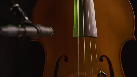 manos masculinas tocando el bajo mientras graban con un micrófono en primer plano