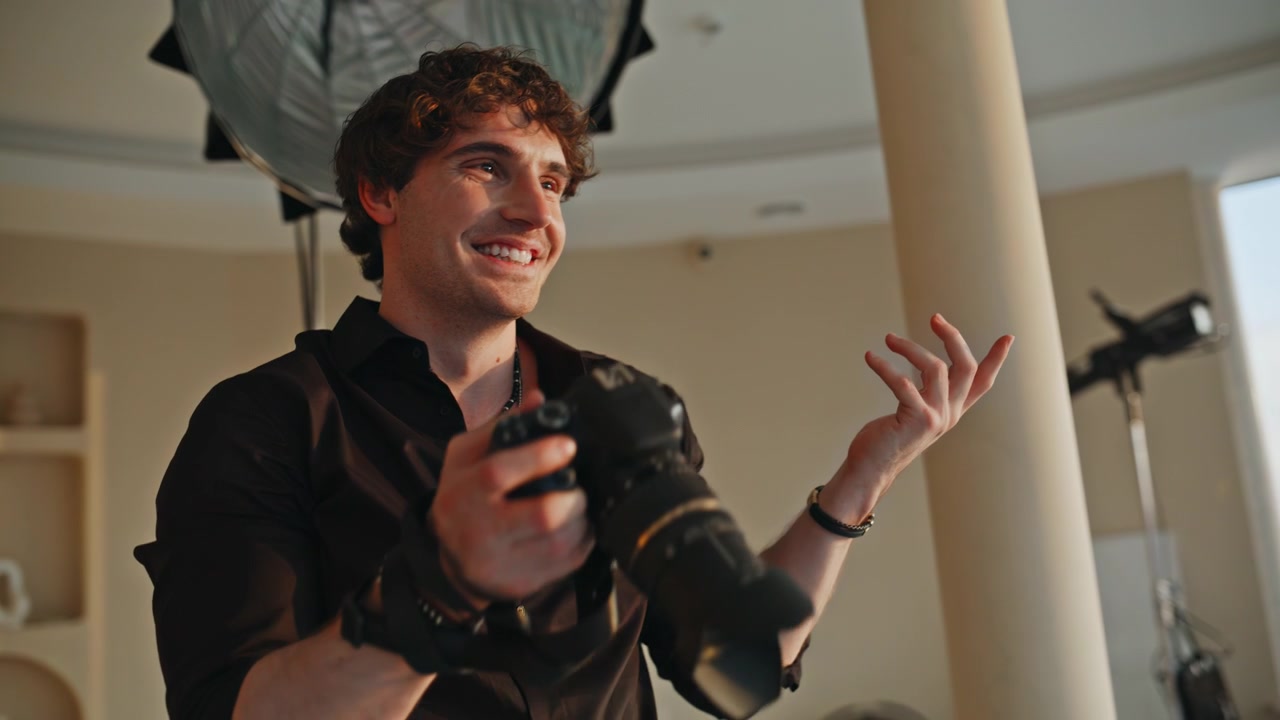 Male photographer reviewing photos on camera studio. Smiling man checking shots.