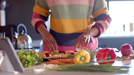 Mid-section-of-african-american-woman-preparing-meal-in-sunny-kitchen