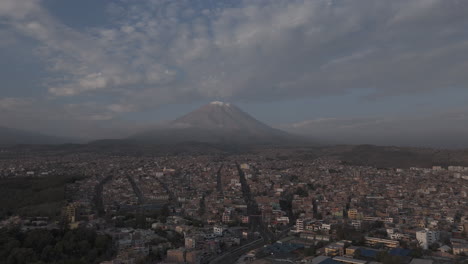 backwards moving drone shot above arequipa peru with view on the mountain near sunset time with clouds in the sky log