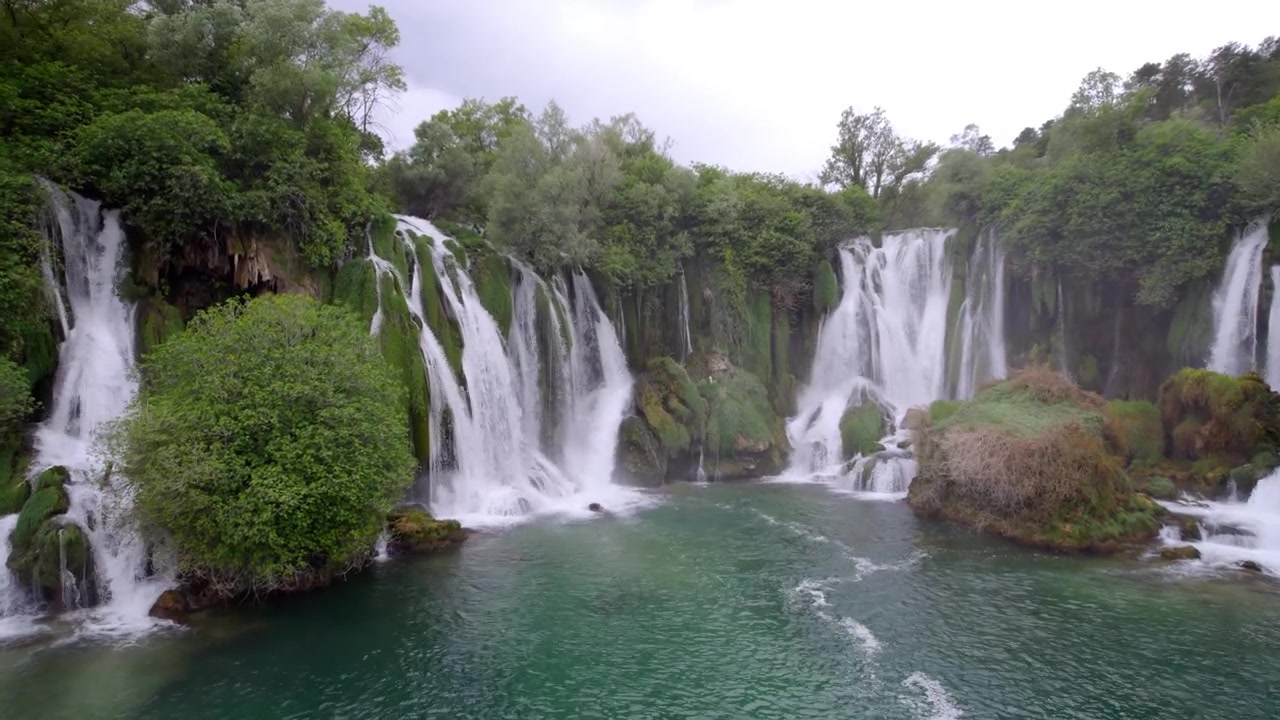 La cascata di Kravica si getta in una calma piscina color smeraldo incorniciata da alberi lussureggianti in Erzegovina, ripresa con drone a bassa quota