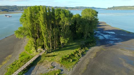 Rising-above-Aucar-island-in-Quemchi,-Chiloé-archipelago-at-sunset,-floating-cemetery,-Chile