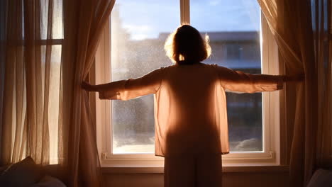 woman opening curtains to a bright morning sun