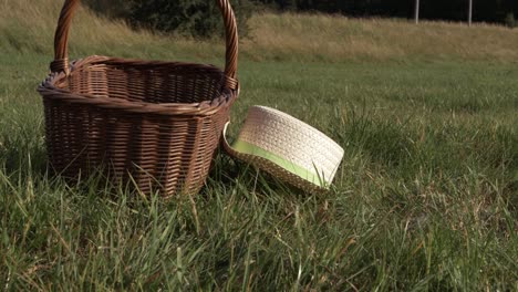 Straw-hat-and-woven-basket-in-a-field-medium-panning-shot