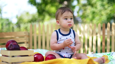 adorable calm baby boy sitting peacefully in the garden in summer. lovely kid with sweet plump cheeks watching the soap bubbles fly. blurred backdrop.