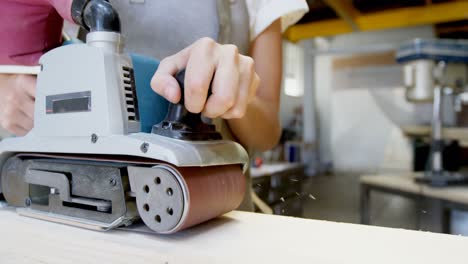 female welder using wood sanding machine 4k