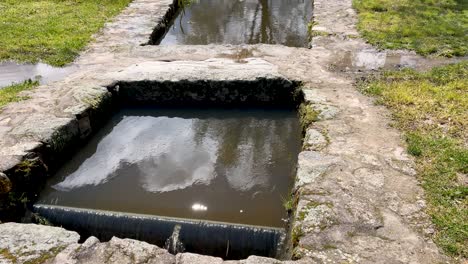 slow motion filming of different departments of a stream channeled with stones and we see that it has small waterfalls. raising the camera we discover the surroundings of the stream