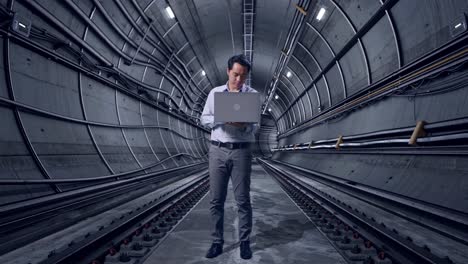 full body of an asian male professional worker standing with his laptop in underground subway tunnel, he is nodding his head with dissapionted