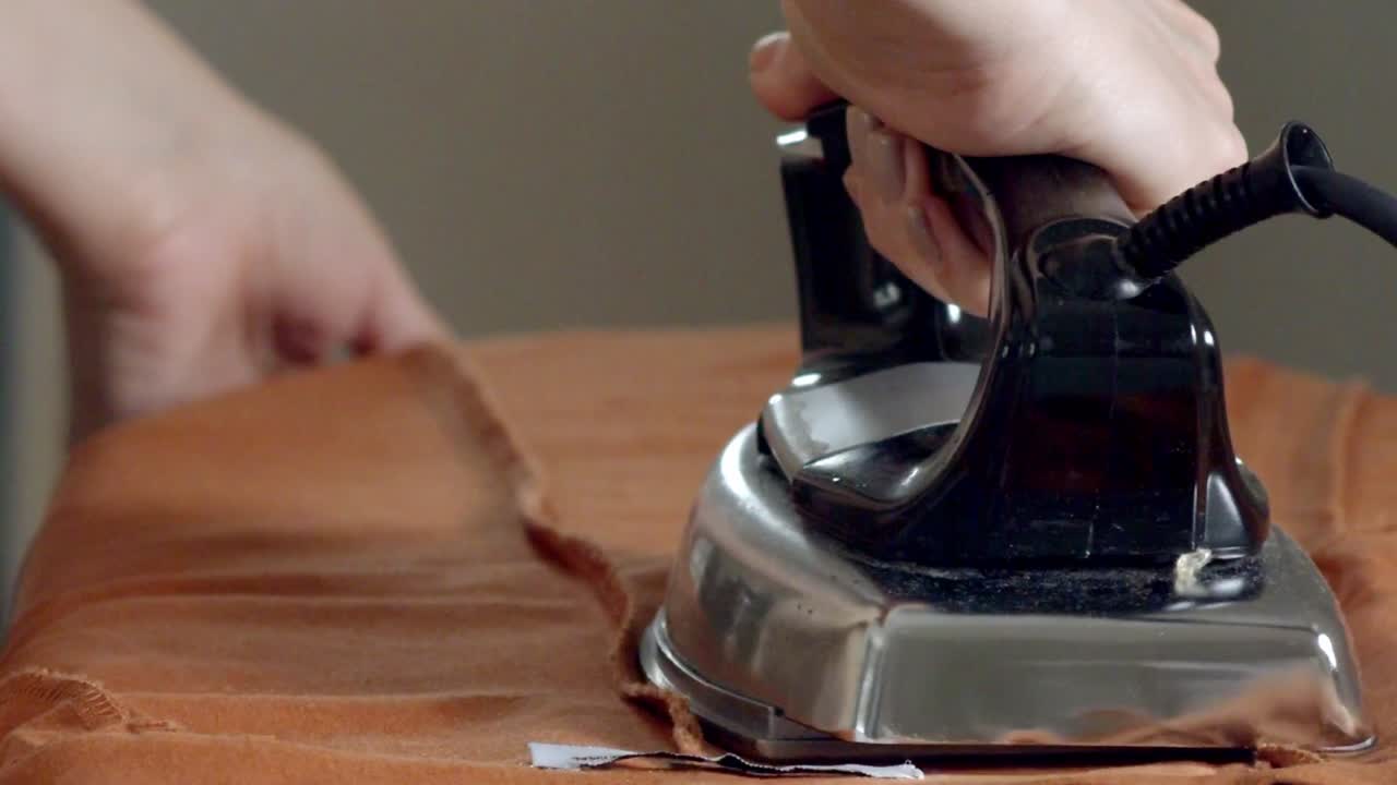 Ironing fabric in a sweatshop - isolated on a person's hand and the ironing board