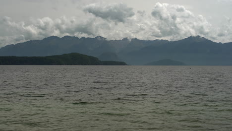 The-serene-lake-in-Fiordland,-New-Zealand,-framed-by-the-lush-mountain-trees-in-the-background,-creates-a-dramatic-vista