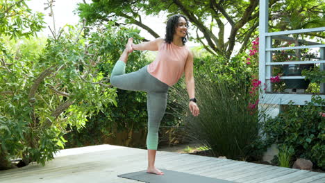 woman practicing yoga on deck surrounded by lush greenery