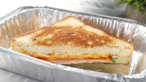 toasted sandwich in aluminum foil container