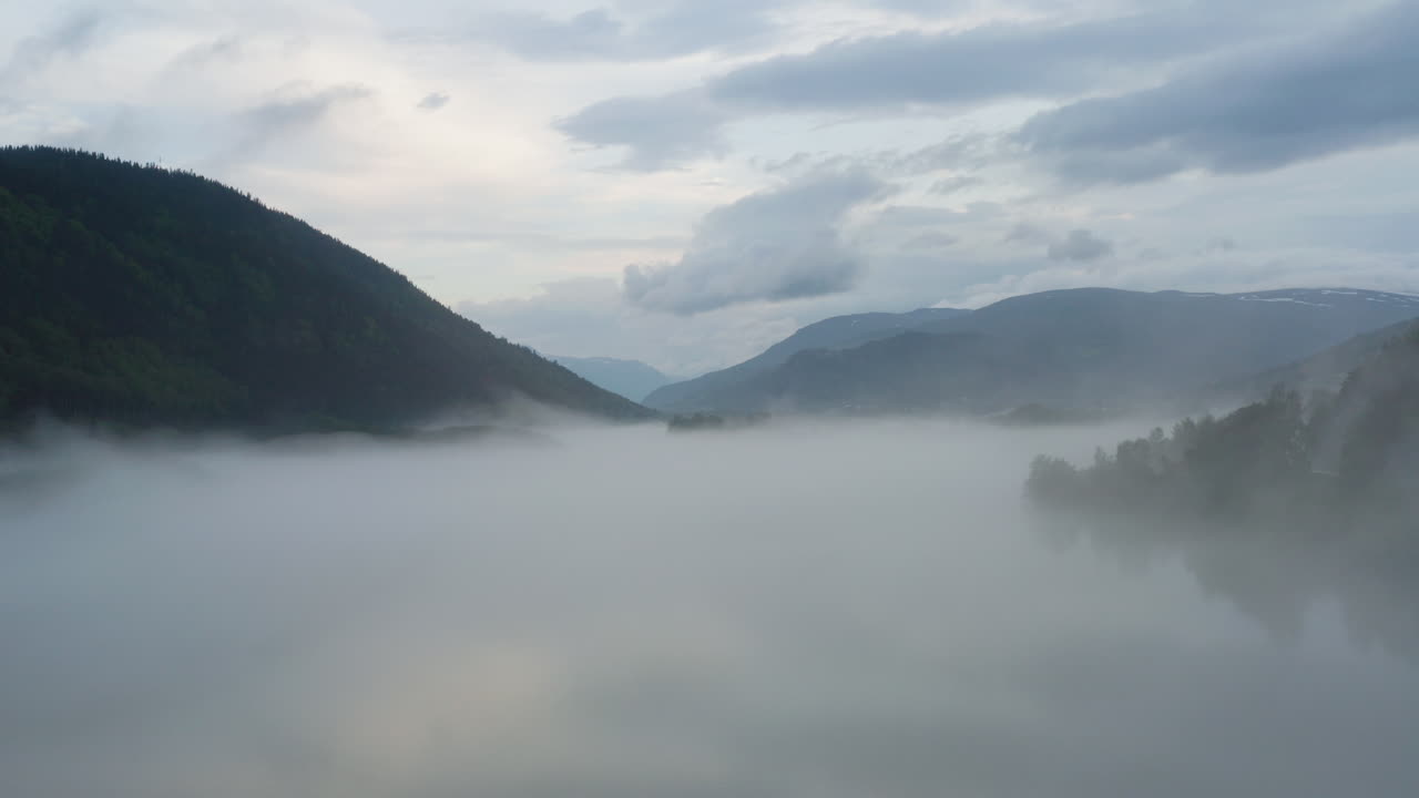 Flight over a foggy river. The mist is hanging low over the landscape creating a dark mystical mood over the whole scene.