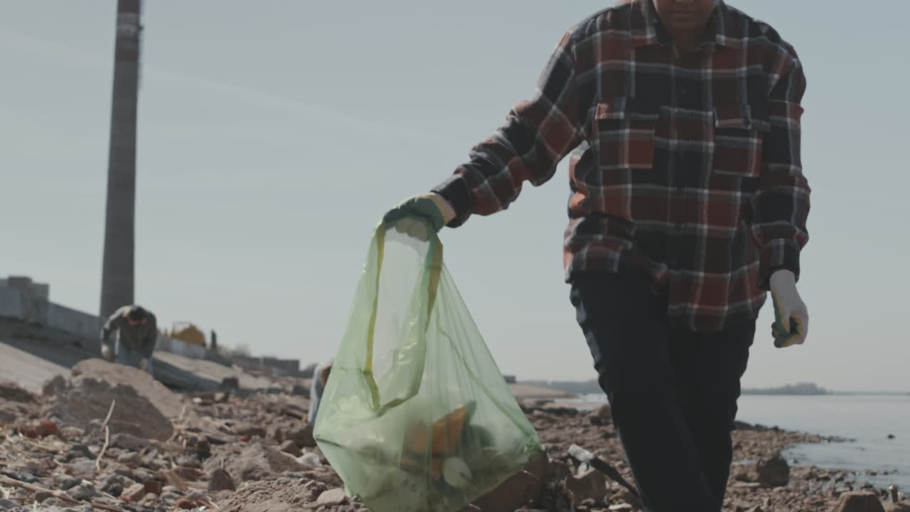 Woman Collecting Garbage on Coastline with Environmental Activists