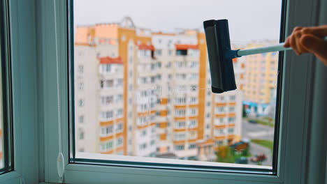 cleaning window with modern brush indoors. worker washing window with a special brush on the background of multi-storey building.