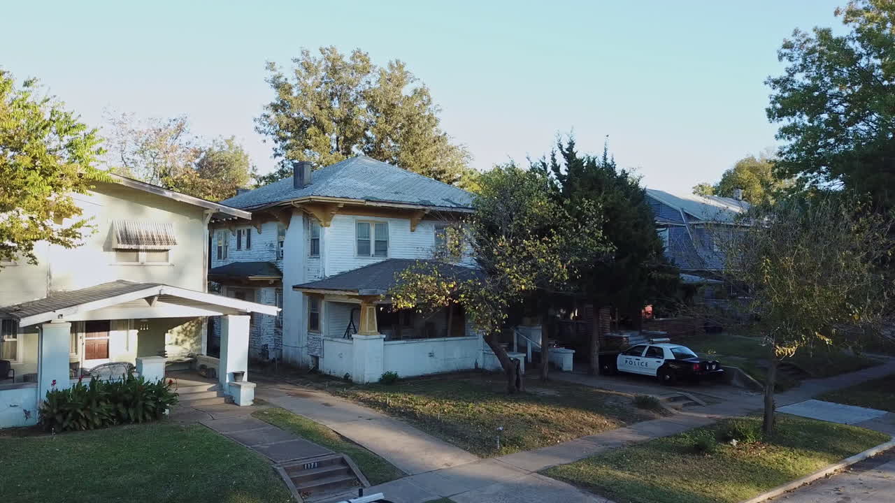 toma aérea estática de algunas casas residenciales con un coche de policía en la entrada
