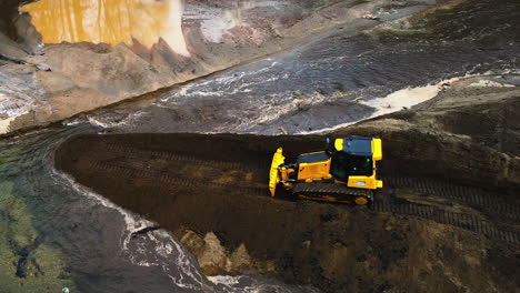 bulldozer backtrack to push dirt in order to stop the flow of a river