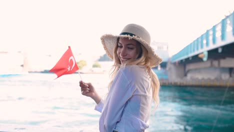 beautiful girl waves turkish flag over galata bridge and enjoys view of bosphorus in istanbul,turkey