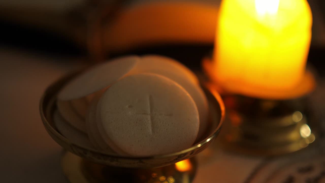 hostias de la comunión en el crepúsculo iluminadas por la luz de una vela encendida