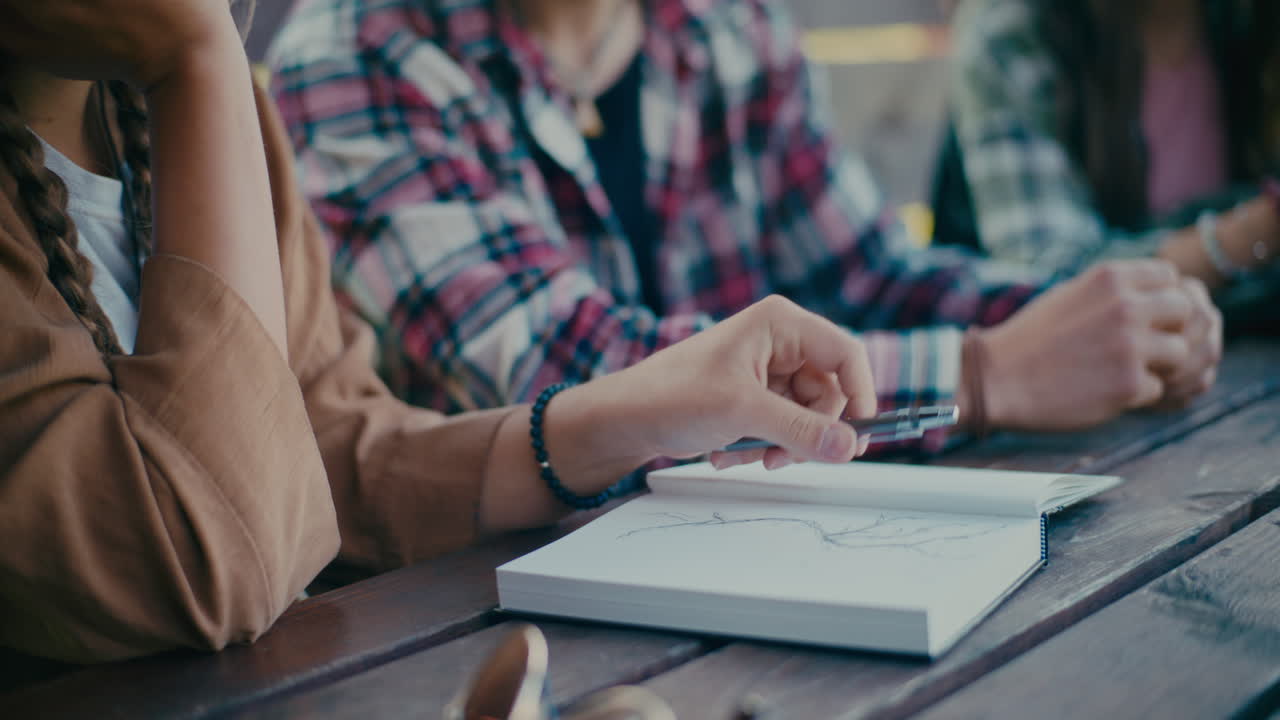 mujer escribiendo en un diario mientras está sentada al lado de un amigo
