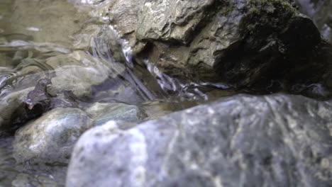 Nahaufnahme-Eines-Kleinen-Baches-In-Den-Schweizer-Alpen,-Der-Zwischen-Steinen-Fließt