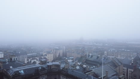 Aerial-view-backwards-passing-the-St-Giles-cathedral,-in-foggy-Edinburgh,-Scotland